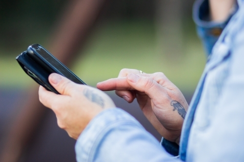 Woman holding phone using to fill in form - Australian Stock Image