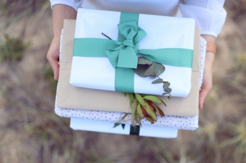 Woman holding presents at beach - Australian Stock Image