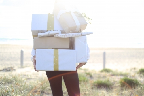 Woman holding presents with beach in background - Australian Stock Image