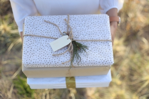 Woman holding presents with sea grass in background - Australian Stock Image