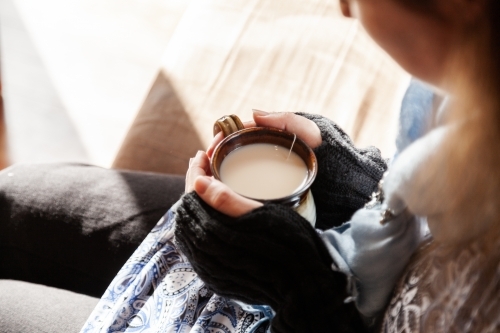 Woman holding warm mug of chai tea in winter - Australian Stock Image