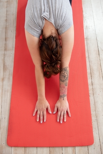 woman in child's pose on red yoga mat in studio