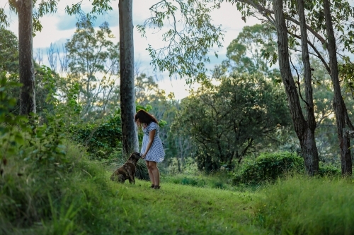 Woman in forest setting showing affection to pet dog - Australian Stock Image