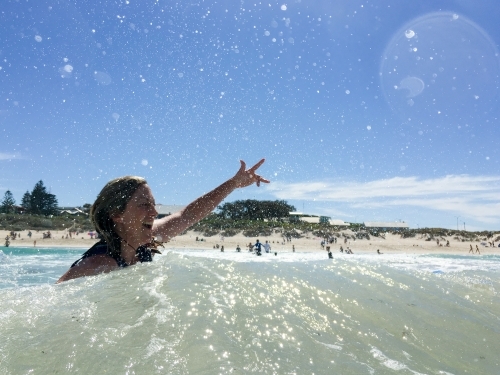 Woman in the ocean signalling positive attitude - Australian Stock Image