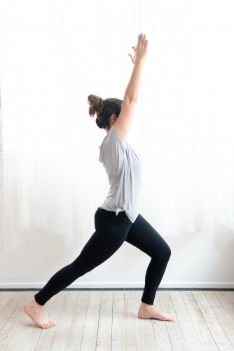 woman in warrior yoga pose in studio