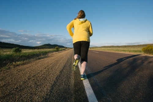 Woman jogging away on a remote country road