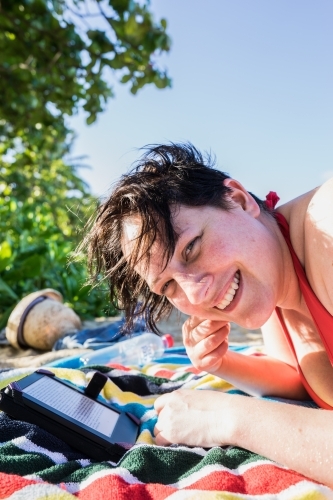 Woman laying on a towel at the beach reading - Australian Stock Image