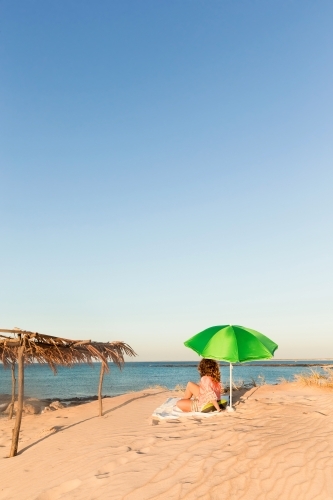 Woman lying under a beach umbrella on the sands of cape leveque - Australian Stock Image