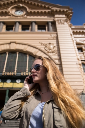 Woman on her phone outside Flinders Street Station - Australian Stock Image