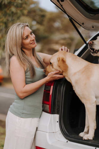 Woman petting her dog in the car boot. - Australian Stock Image