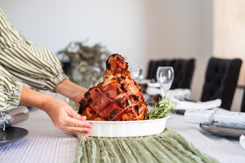 woman placing christmas ham on the table - Australian Stock Image