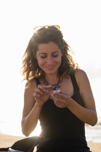 woman putting on lip balm at the beach - Australian Stock Image