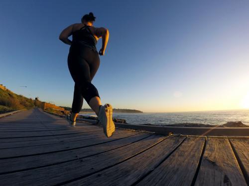 Woman running along ocean boardwalk at sunrise