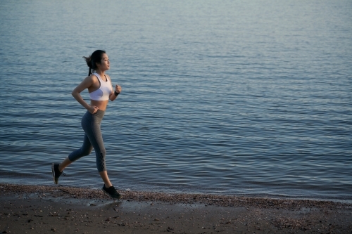 Woman running along waterside for morning exercise
