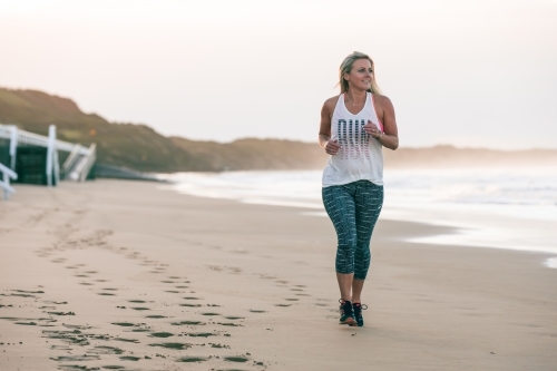 woman running on the beach in the early morning - Australian Stock Image