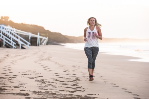 woman running on the beach in the early morning - Australian Stock Image