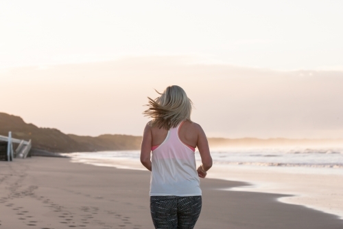 woman running on the beach in the early morning - Australian Stock Image