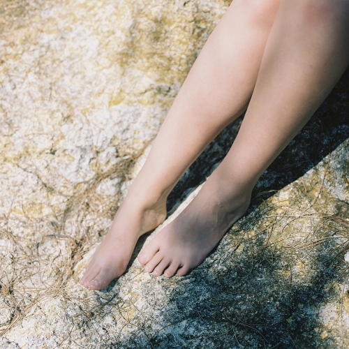 Woman's Naked Legs on Beach Rock