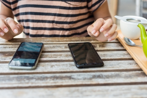 woman sharing info from one phone to another - Australian Stock Image