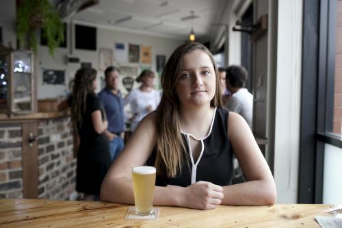 Woman sitting behind table at local craft beer bar - Australian Stock Image