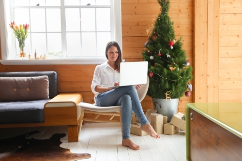 Woman sitting in front of Christmas tree with laptop