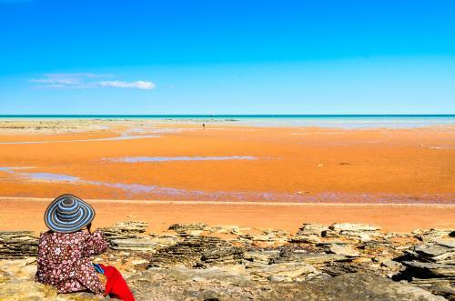 Woman sitting on beach at low tide looking out at sea