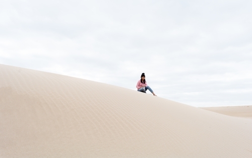 Woman sitting on sand dunes