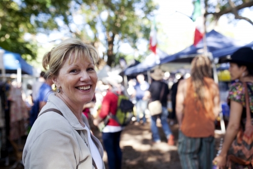 Woman smiling and walking through an outdoor market - Australian Stock Image