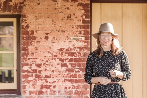 Woman smiling in front of a rustic house - Australian Stock Image