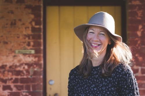 Woman smiling in front of a rustic house - Australian Stock Image