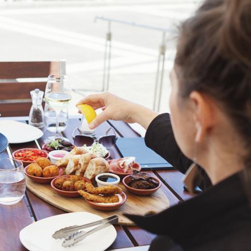 Woman squeezing lemon over antipasto platter at lunch - Australian Stock Image