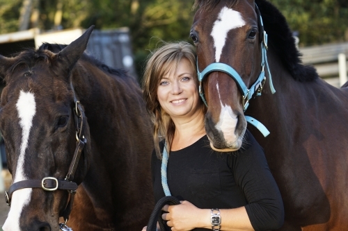 Woman standing between two horses