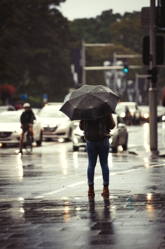 Woman standing in rain with umbrella - Australian Stock Image