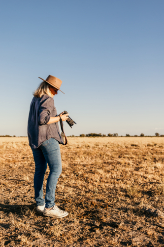 Woman standing looking down at camera outdoors on farm - Australian Stock Image