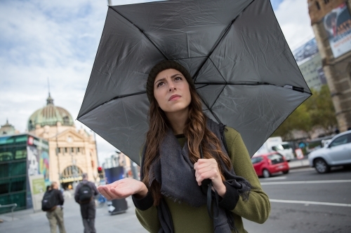 Woman standing with umbrella in classic Melbourne Weather