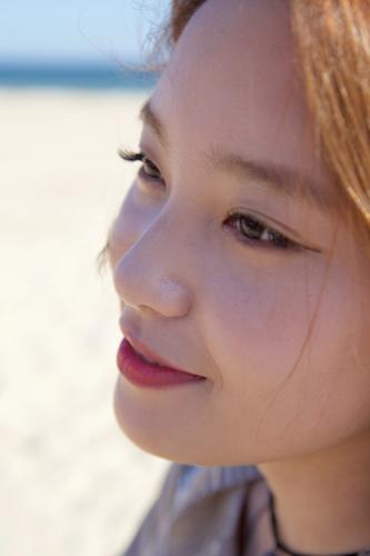 Woman staring pensively with the beach behind her - Australian Stock Image