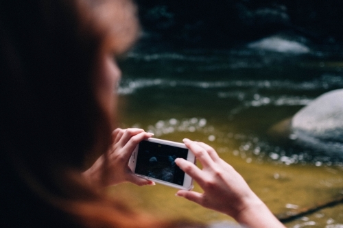 Woman taking photos with phone camera in Mossman Gorge