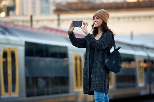 Woman talking photo with mobile phone at train station - Australian Stock Image