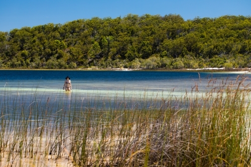 Woman wading along the shallow water of a lake - Australian Stock Image
