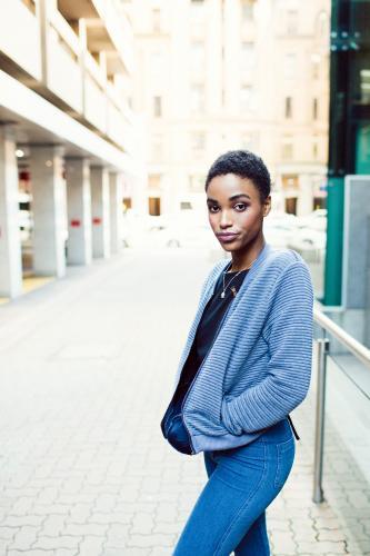 Woman walking along street with hands in pockets - Australian Stock Image