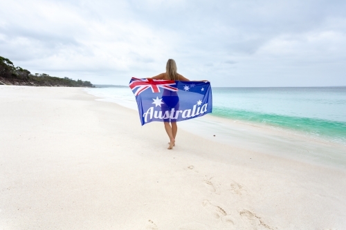 Woman walking along the beach holding Australian Flag - Australian Stock Image