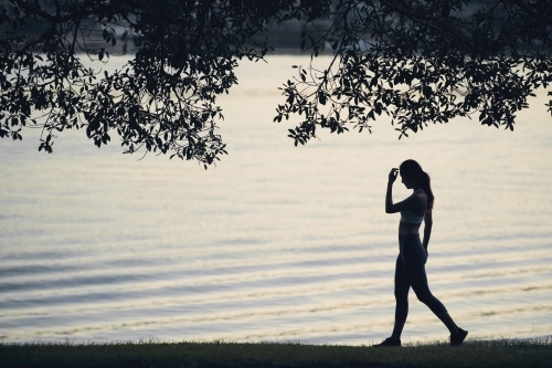 Woman walking along waterside for morning exercise