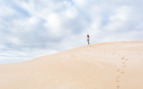 Woman walking away over sand dune