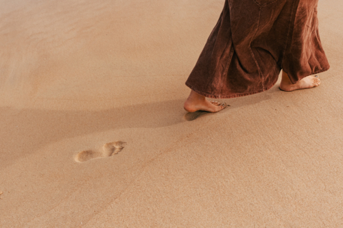 woman walking in sand leaving footprint - Australian Stock Image
