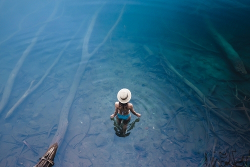 Woman walking into clear water at lake - Australian Stock Image
