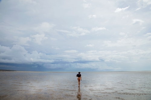 Woman walking out across shallow water - Australian Stock Image