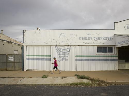 Woman walking past old butcher shop on an overcast day