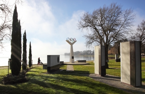 Woman walking pram past Olympic rings Monument - Australian Stock Image
