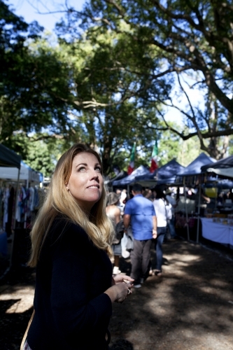 Woman walking through an outdoor market looking up - Australian Stock Image