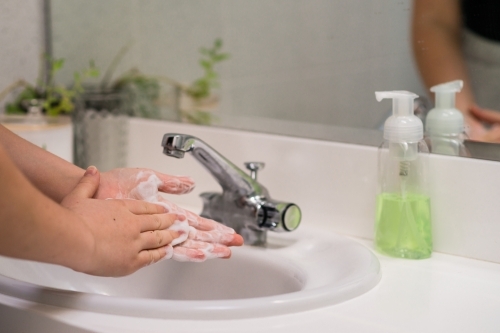 woman washing hands in basin - Australian Stock Image